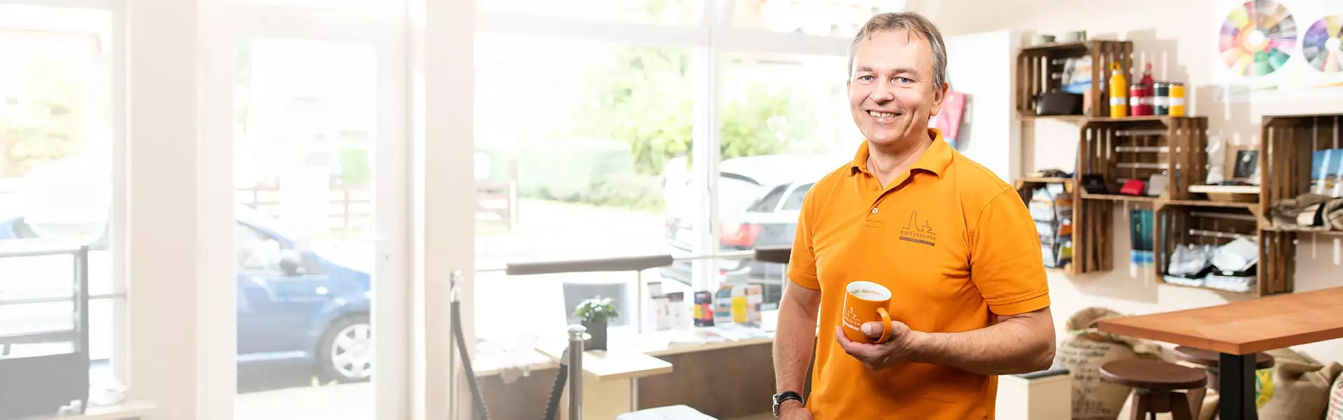 Lächelnder Mann von der Kaffeeküste Laboe mit Kaffeetasse in der Hand